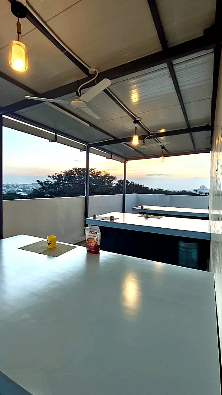 CO-WORK @ Level 3 — the roof terrace at dusk, long tables under a light steel canopy looking out over the city