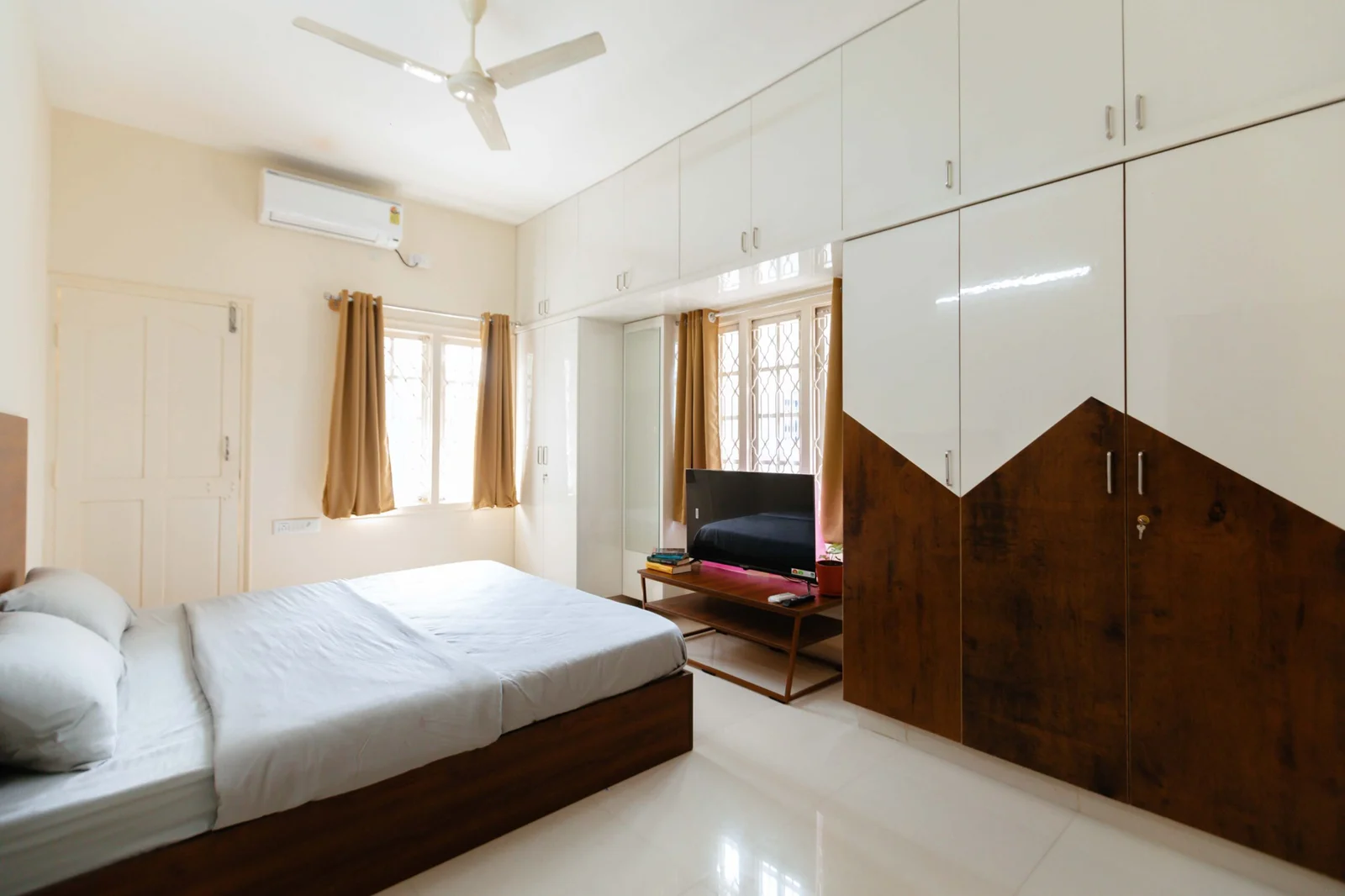 PRAAD Suites — bedroom with full-height wardrobes and a study corner