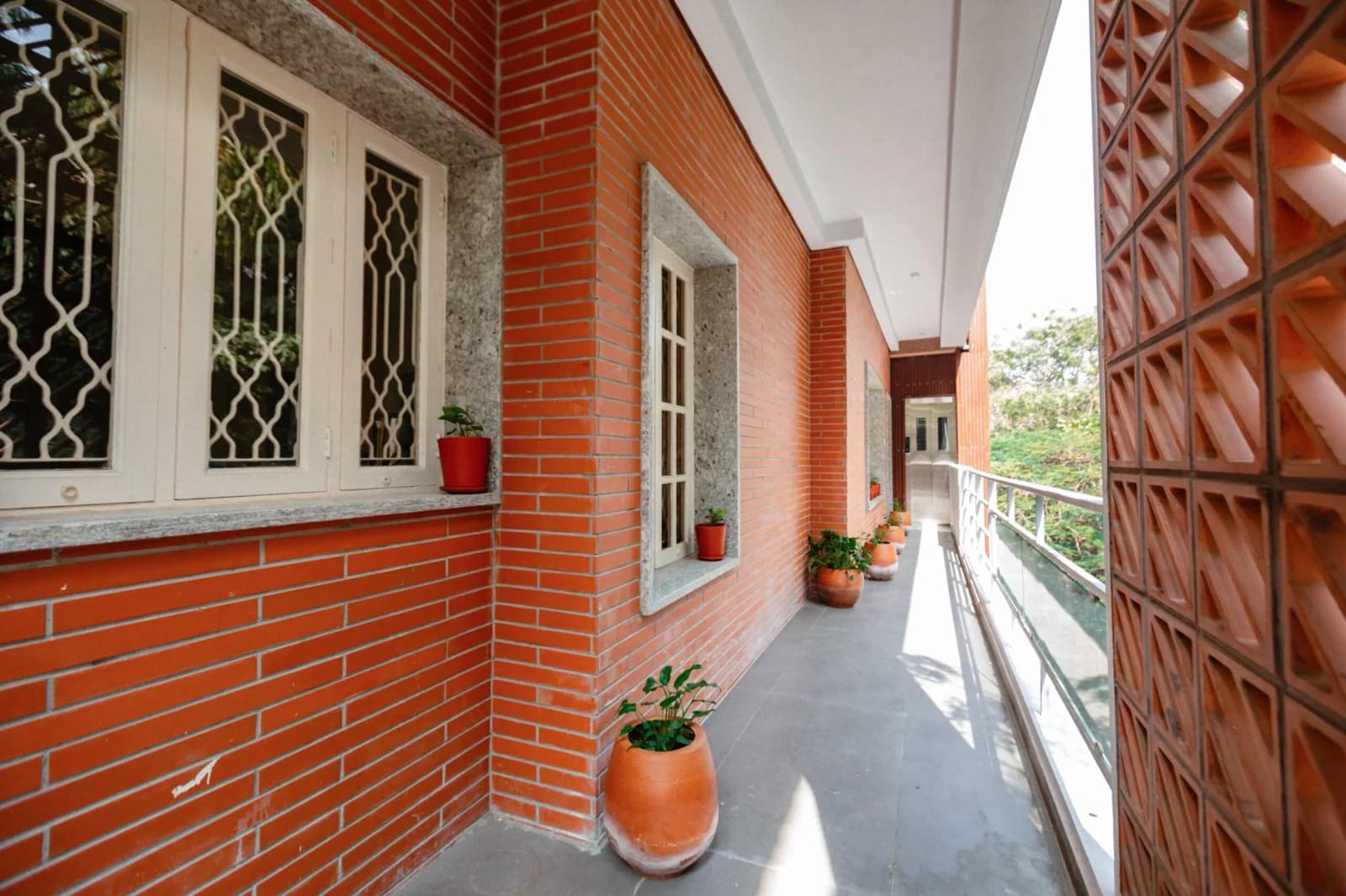 PRAAD Suites — open gallery corridor lined with planted terracotta